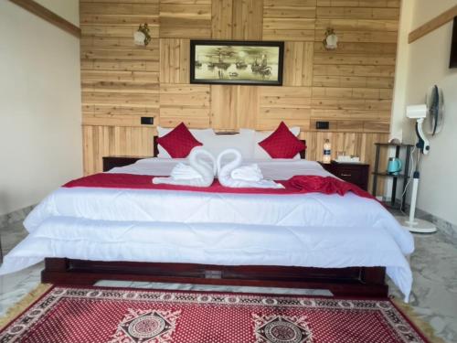 a bedroom with a large white bed with red pillows at JMS Resort in Cherrapunji