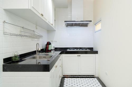 a white kitchen with a sink and a stove at Latkrabangbishome Near Suvarnabhumi Airport ลาดกระบังบิซโฮม in Lat Krabang