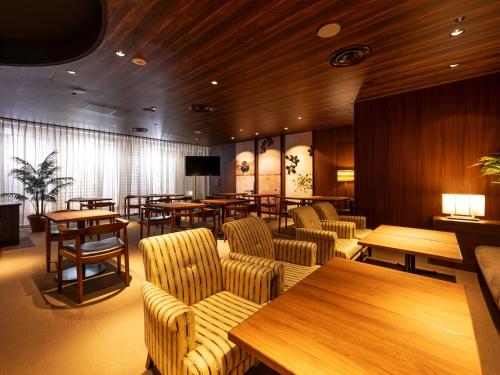 ANA Crowne Plaza Akita, an IHG Hotel في أكيتا: مطعم به طاولات وكراسي وجدران خشبية