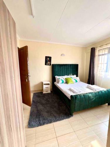 a bedroom with a green bed with a green couch at Luxe suite (1bedroom) in Nambale