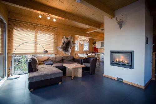 sala de estar con sofá y chimenea en Alpenpark Turrach by ALPS RESORTS en Turracher Hohe