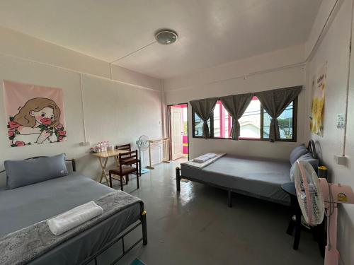 a bedroom with two beds and a table in it at Madam Guesthouse in Krabi town