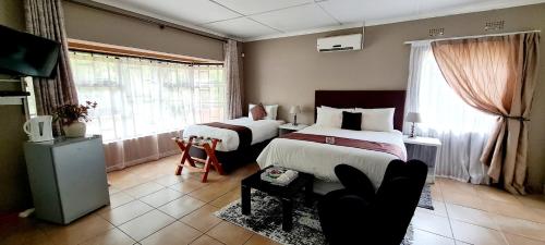 una camera d'albergo con due letti e un divano di Thamalakane guest house a Maun