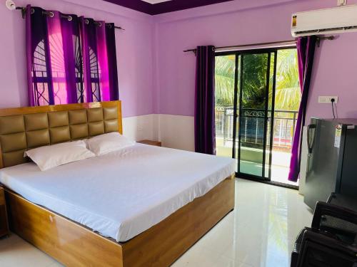 1 dormitorio con 1 cama con paredes de color púrpura y ventana en Susegado by js apartment en Calangute