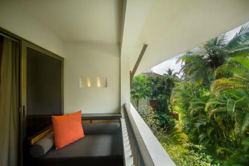 a balcony with an orange pillow sitting on a bench at Alila Diwa Goa - A Hyatt Brand in Majorda