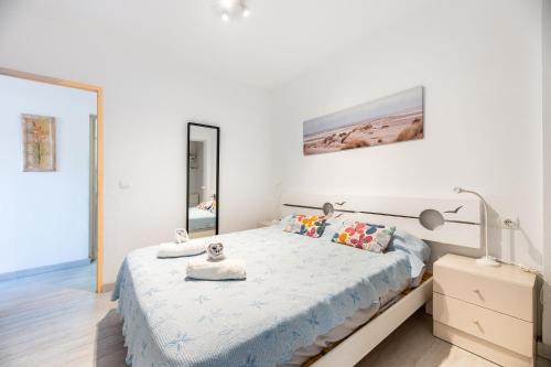 a white bedroom with a large bed and a mirror at Apartamento los Hermanos in Es Pujols