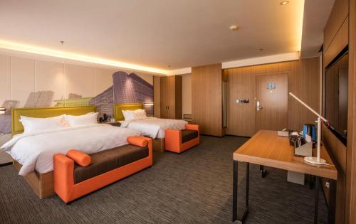 大連市にあるMehood Hotel Dalian Hi-tech Wanda Plaza Xinghaiのベッド2台とデスクが備わるホテルルームです。