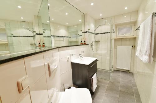 a bathroom with a toilet and a sink and mirrors at Ferienwohnungen Kohler komplett neu renoviert !!!!! in Mittelberg