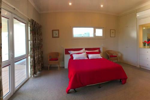 ein Schlafzimmer mit einem roten Bett und einem Fenster in der Unterkunft Beckworth Retreat - Ahh, the serenity! in Clunes