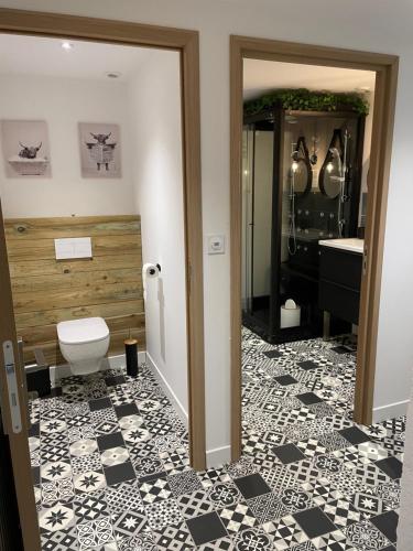 a bathroom with a toilet and a black and white tile floor at Fermette des Luarts in Coudrecieux