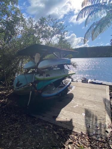 a row of surfboards sitting on a dock next to a lake at Luxury Lake House Retreat in Mangakino