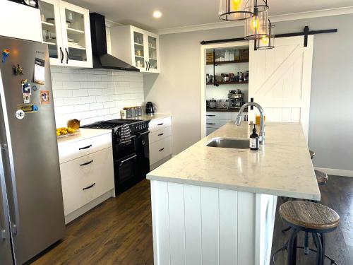 a kitchen with white cabinets and a sink and a refrigerator at Luxury Lake House Retreat in Mangakino