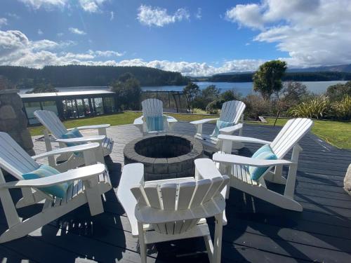 a group of white chairs sitting around a fire pit at Luxury Lake House Retreat in Mangakino