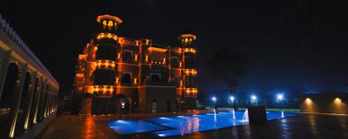 een groot gebouw met 's nachts verlichting bij The Biletha Bagh in Udaipur