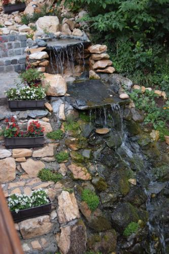 a rock garden with a waterfall and flowers in pots at Motel Lepo Mesto in Strmosten