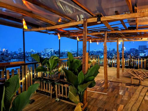 una terraza en la azotea con vistas a la ciudad por la noche en The GK House Hostel, Ecolliving, central city, natural wooden, chill view rooftop, reétaurant and cocktail bar, en Ho Chi Minh