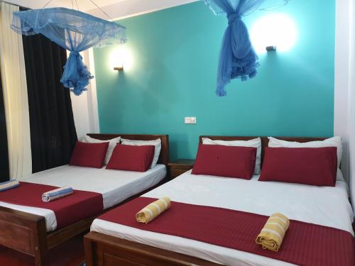 two beds in a room with red and blue walls at Raymond Place -REDSTAR in Weligama