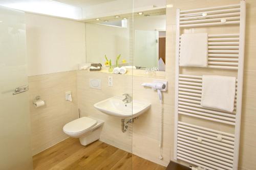 a white bathroom with a sink and a toilet at Braustüble und Hotel zur Post in Weiler-Simmerberg