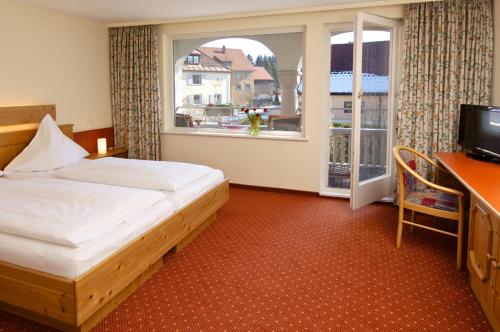 Schlafzimmer mit einem Bett, einem Schreibtisch und einem Fenster in der Unterkunft Braustüble und Hotel zur Post in Weiler-Simmerberg