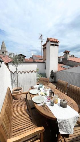 a wooden table and chairs on a balcony at Charmantes Altstadthaus mit Dachterrasse in Muggia