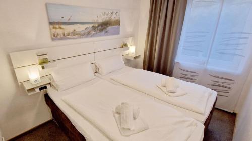 a room with two beds with white sheets at Haus-Schwalbennest-Whg-03 in Olsdorf