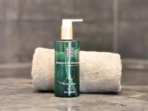 a green bottle of soap sitting next to a towel at Fynbos Deluxe, Penthouse oder Balkon, Parkplatz in Straubing
