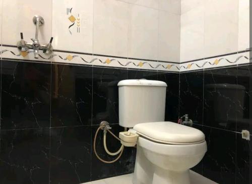 ein weißes WC im Bad mit schwarzen Fliesen in der Unterkunft The happy shack in Jaipur