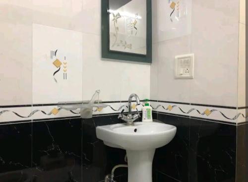 ein Bad mit einem weißen Waschbecken und schwarzen und weißen Fliesen in der Unterkunft The happy shack in Jaipur