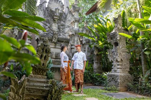 a man and a woman standing in front of a temple at The Hava Ubud A Pramana Experience in Ubud