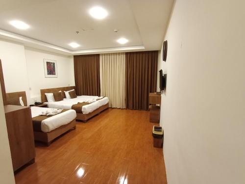 a hotel room with two beds and a couch at Soulmate Hotel Erbil in Erbil