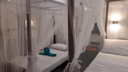 a bedroom with two beds with white curtains and a blue stuffed animal at Taco Kings Place in Unawatuna