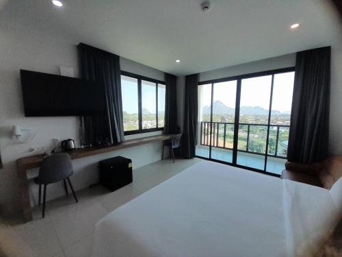 a bedroom with a large bed and large windows at Mountain&Sea Hotel Prachuap in Prachuap Khiri Khan