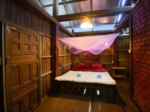 een kamer met een bed met een klamboe bij Backpacker Hostel and Jungle Trekking in Banlung