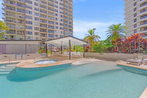 a swimming pool with an umbrella and some buildings at Burleigh Beach Tower in Gold Coast