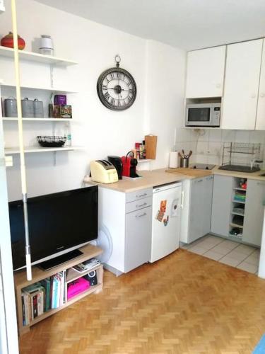 Il comprend une cuisine équipée d'un réfrigérateur et d'une horloge murale. dans l'établissement Studio avec terrasse aux Portes de Paris, aux Lilas
