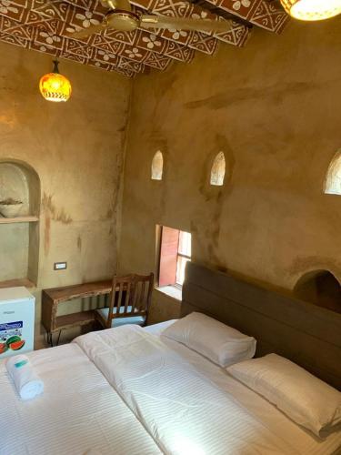 a bedroom with a bed and a table and a window at بيت النحوي التراثي _ Bait Al Nahwai in Al Ḩamrāʼ