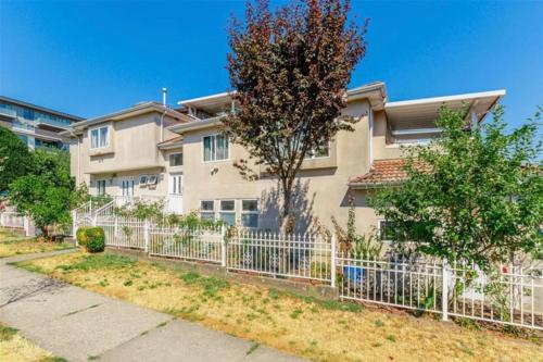 a white fence in front of a house at Llt Fraser HomeAway in Vancouver