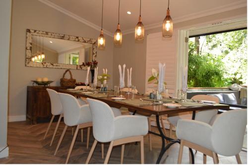 a dining room with a long table and white chairs at Green Elephant in Lilongwe