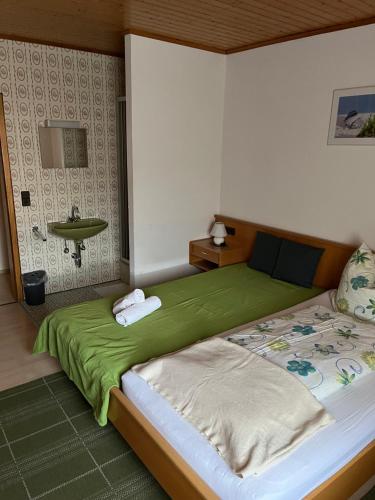 a bedroom with a large bed with a green blanket at Lenche Gasthaus Neumayer 