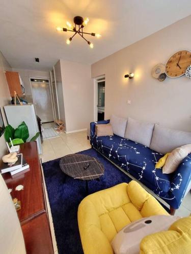 een woonkamer met een blauwe bank en een gele stoel bij 1 Bedroom Apartment on Kiambu Road in Kiambu