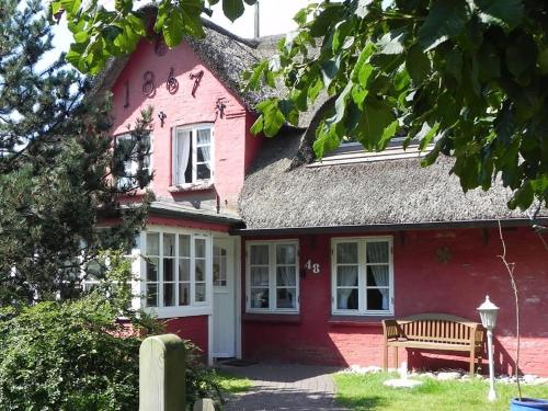a red house with a bench in front of it at Hüs Sanskiin Ferienwohnung *Aawerkant* in Süddorf