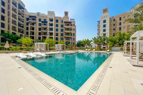 una piscina con sillas y edificios en el fondo en FAM Living - Serene 1BR Haven in Madinat Jumeirah Living, en Dubái