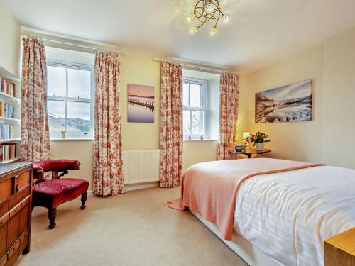 a bedroom with a bed and a chair and windows at 1 Bed in Matterdale 91812 in Dockray