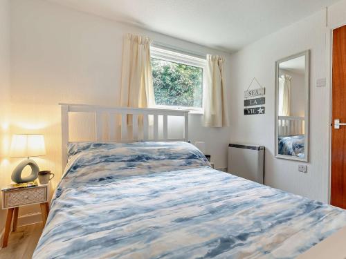 a bedroom with a bed with a blue and white bedspread at 1 Bed in Plymouth 91835 in Turnchapel