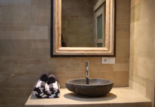 een wastafel in een badkamer met een spiegel en slippers bij INAYA VILLA in Amed