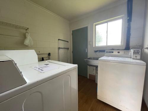 a laundry room with a washer and a sink at Alexandra Motor Lodge in Alexandra