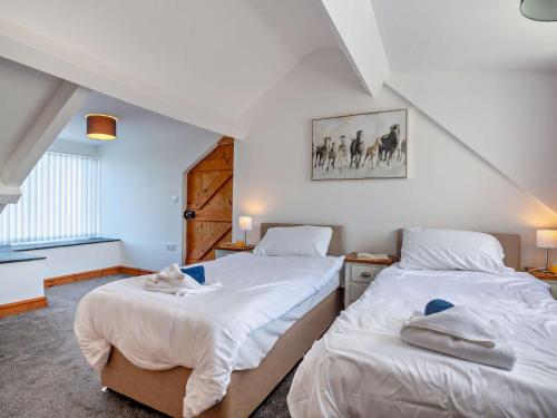 2 camas en una habitación con sábanas blancas en 2 Bed in Aberdesach 92082 en Clynnog-fawr