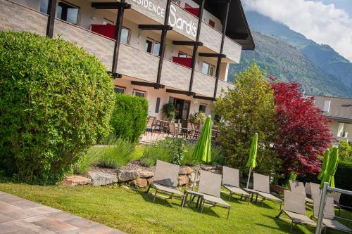 a group of chairs and umbrellas in front of a hotel at Residence Sardis in Castelbello-ciardes
