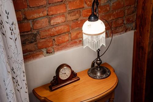 a lamp on a table with a clock on it at Villa Sophia in Biskupiec