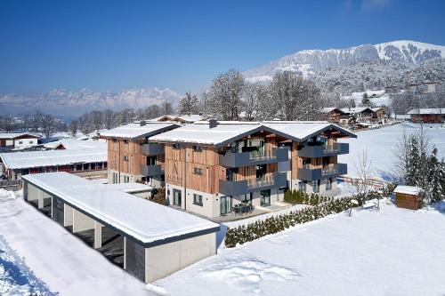 a building in the snow with snow on the roof at Alpin Residenzen Eichenheim Aurach bei Kitzbühel by Alpina-Holiday in Aurach bei Kitzbuhel